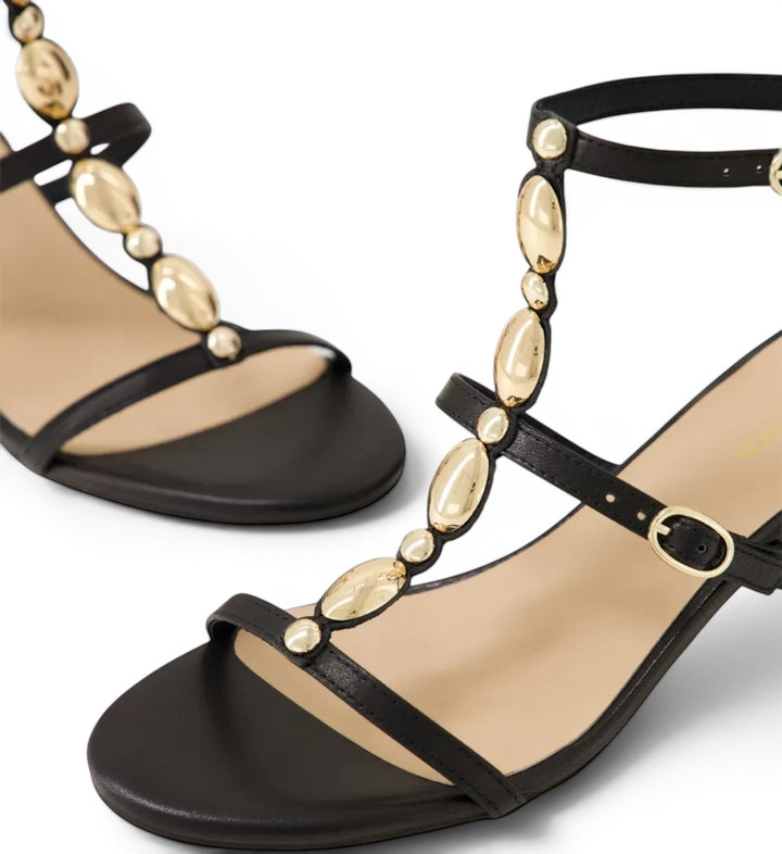House of Florian Glimery Black sandals featuring gold-tone oval embellishments on a t-strap design with buckle closure