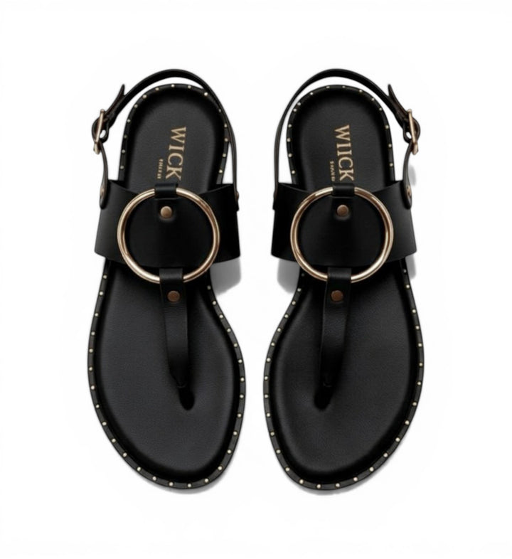 House of Florian Tegan Black leather flat sandals with gold ring detail and stud trim.
