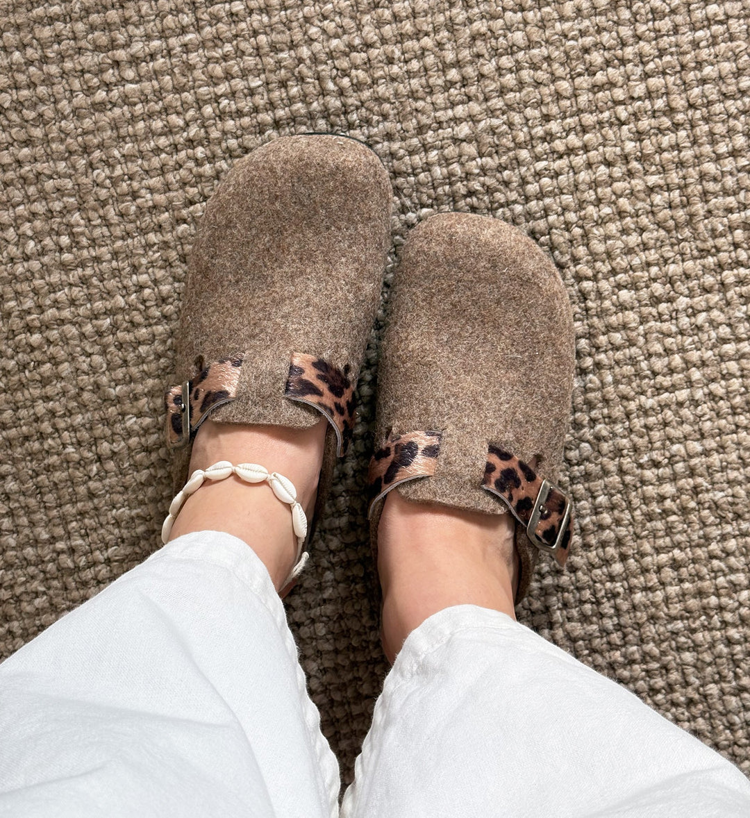 House of Florian Dr Feet  honey camel felt clogs with leopard print strap detail worn with white trousers and shell anklet