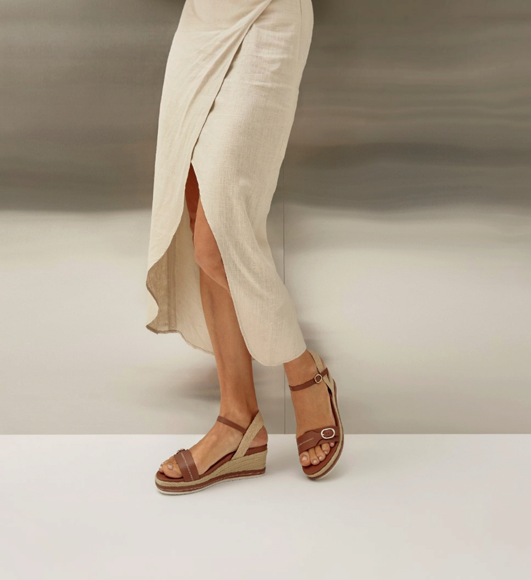 House of Florian Halle Rich Tan wedge sandals with ankle straps and espadrille detailing worn with a beige wrap skirt