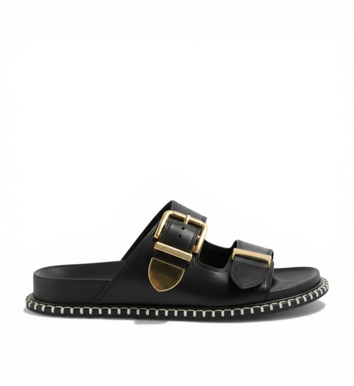 House of Florian Iyami W black leather double strap slide sandals with gold buckles and decorative stitching.