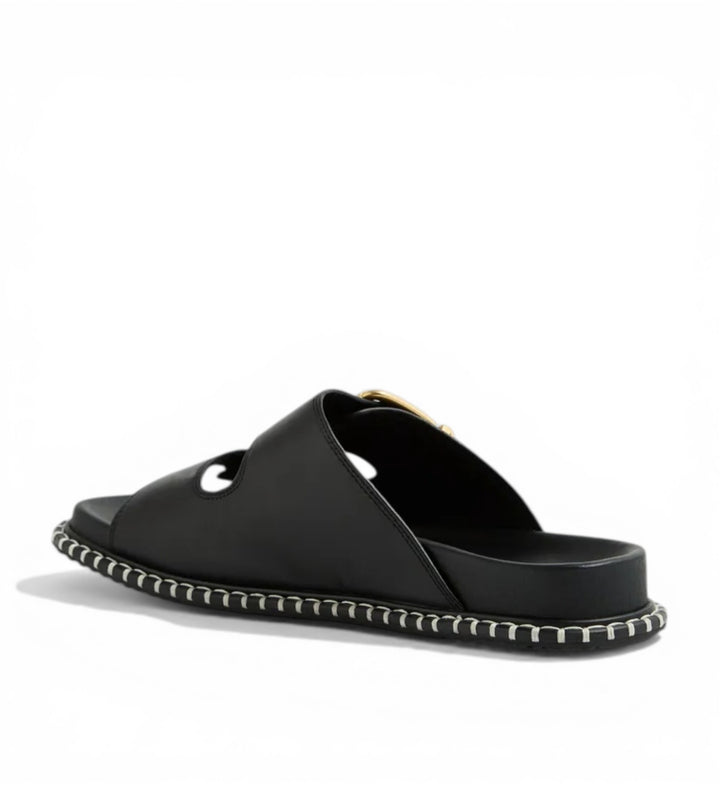 House of Florian Iyami W Black leather slide sandals with a gold buckle and decorative stitching.