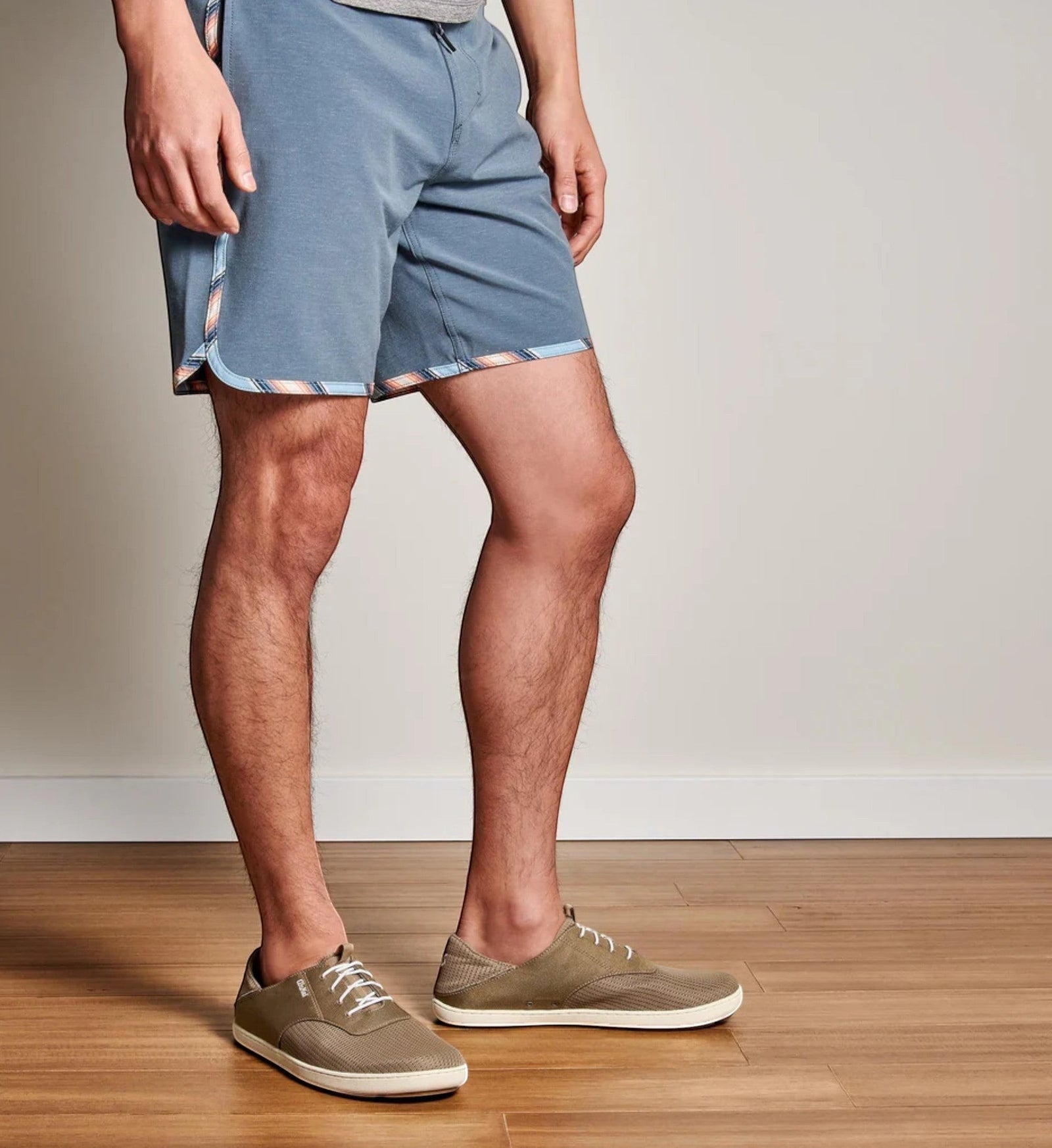 House of Florian men's blue athletic shorts with striped trim and olive green mesh sneakers.