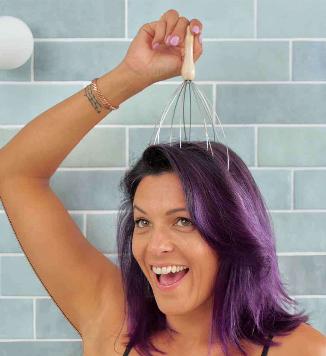 House of Florian multi prong head massager with wooden handle and silver metal prongs being used by a woman with purple hair.