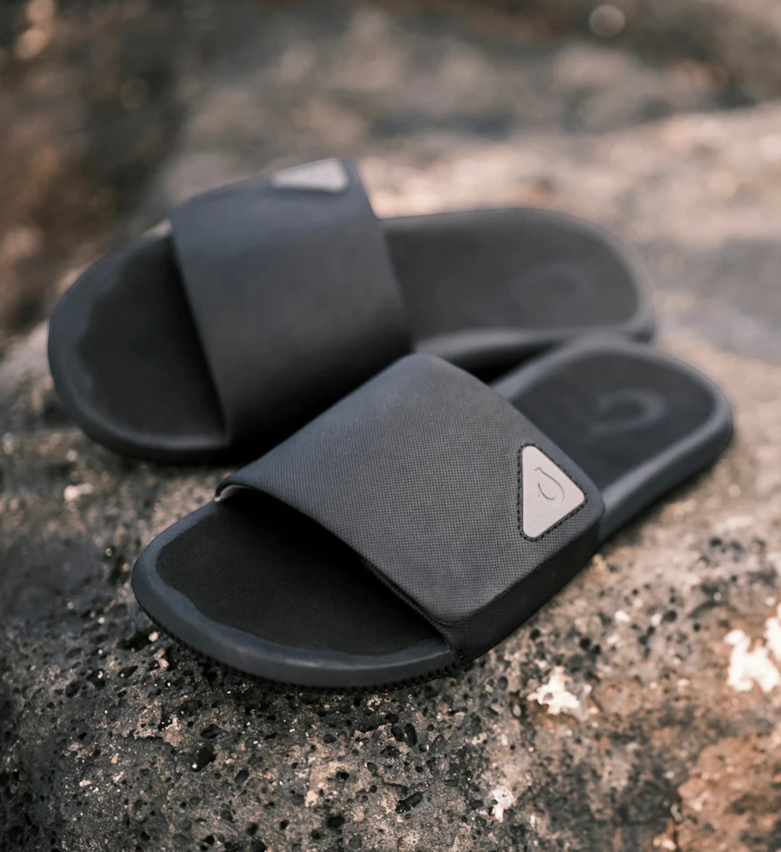House of Florian Ulele Lanai Lava Rock slides in dark grey with textured strap and triangular logo detail.