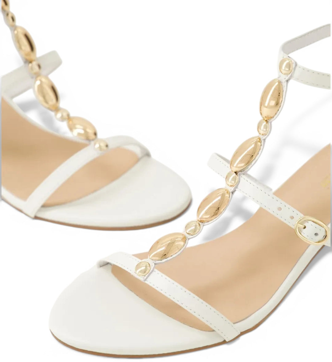 House of Florian Glimery White sandals featuring a t-strap design with gold metallic embellishments and buckle closure.